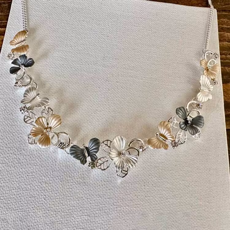 Halsband med fjärilar och blommor i både matta och blanka metallfärger.