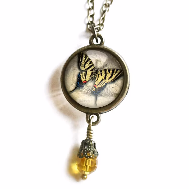 Vintageinspirerat halsband med en illustration av en gul fjäril med en pärla undertill.
