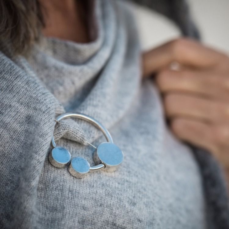 rund silverbrosch med form av omega på sjal. round silver brooch with the design from omega on a shawl.