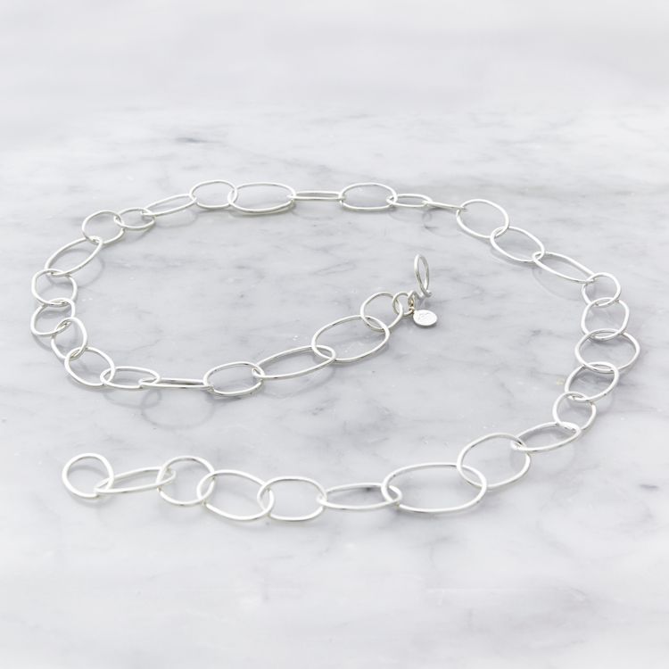 långt silverhalsband med runda länkar i olika storlekar. long silver chain with round links in various sizes.