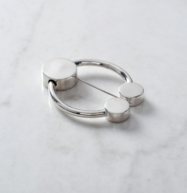 rund silverbrosch med form av omega. round silver brooch with the design from omega.
