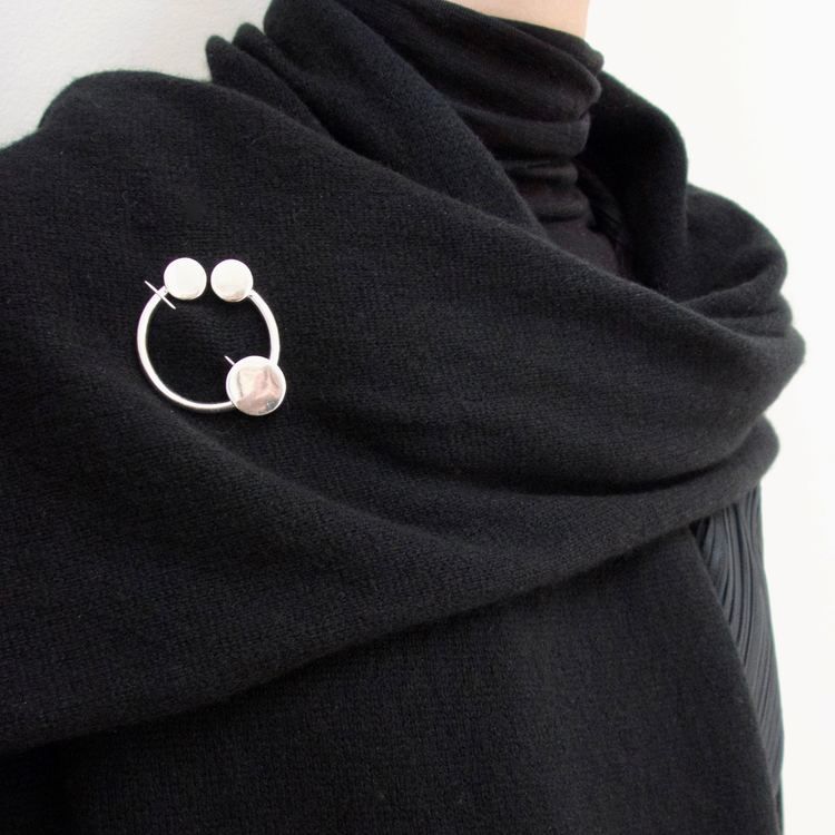 rund silverbrosch med form av omega på sjal. round silver brooch with the design from omega on a shawl.