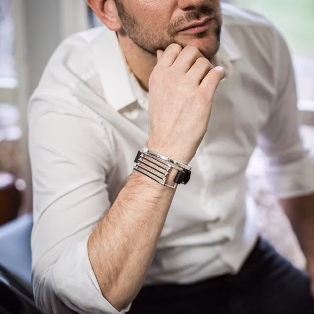 manlig modell som bär två armband med läder och silver. man wearing two silver bracelets with black leather