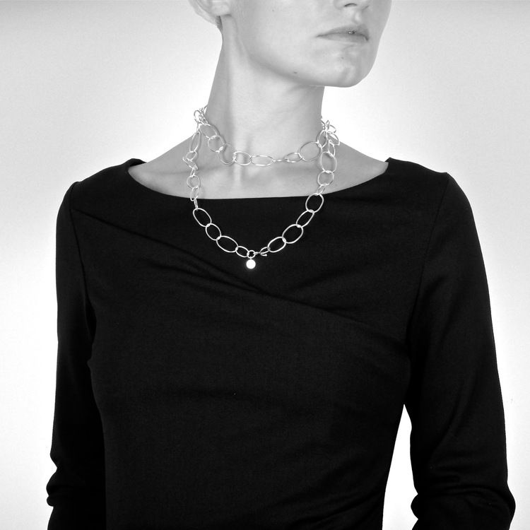långt silverhalsband med runda länkar i olika storlekar. long silver chain with round links in various sizes.