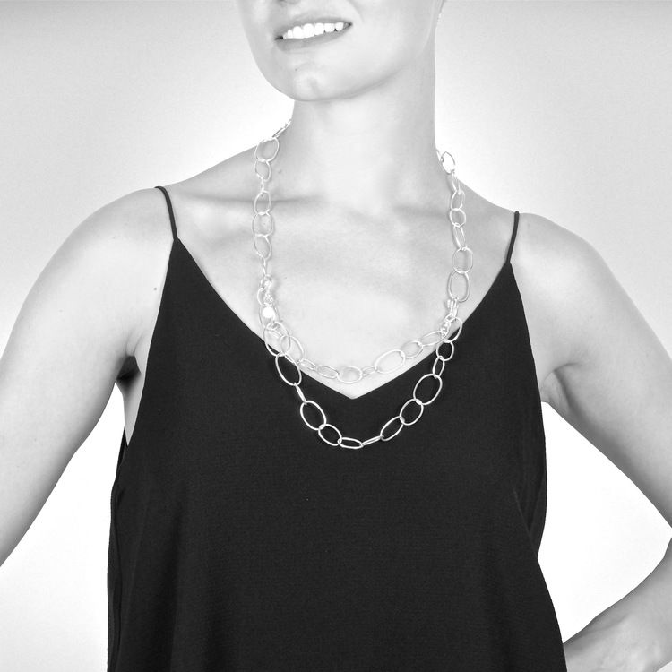 långt silverhalsband med runda länkar i olika storlekar. long silver chain with round links in various sizes.
