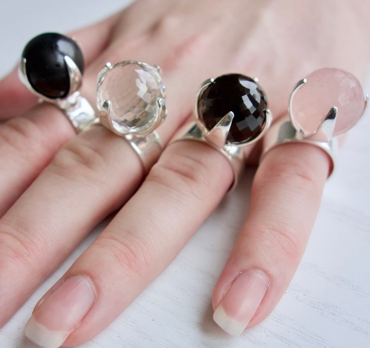 hand med stora silverringar med rosenkvarts, rökkvarts, onyx och kristallkvarts. hand with big silver rings with rose quartz, smokey quartz, onyx and crystal quartz