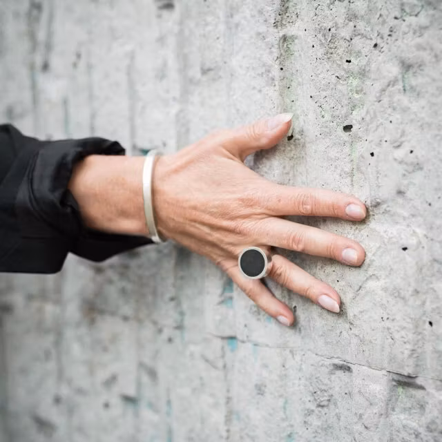 hand på vägg, stor silverring med onyx och silverarmband. hand on wall with bracelet and a big silver ring with onyx