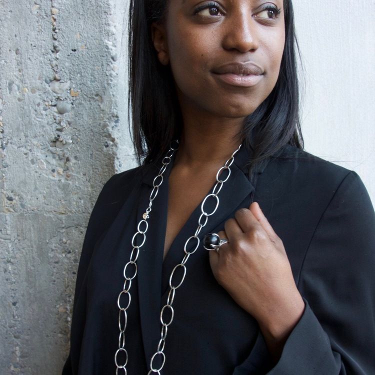 kvinna med långt silverhalsband med runda länkar i olika storlekar. woman with long silver chain with round links in various sizes.