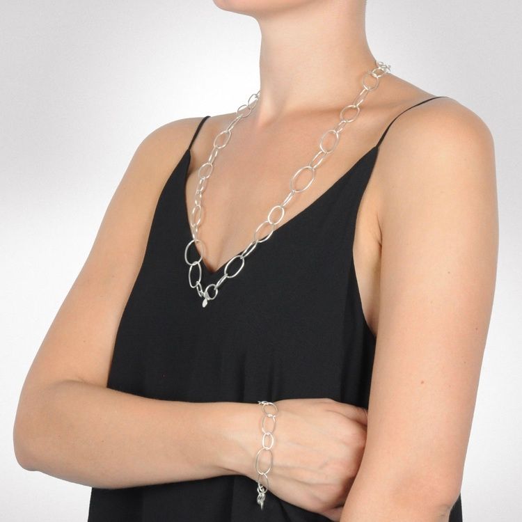 Kvinna med silverarmband och matchande långt silverhalsband. Woman with silver bracelet and matching long silver chain