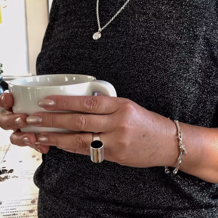 Modell med Model with Silverarmband som är ledat och mjukt format och en stor svart silverring. Model with Silver bracelet with a soft form and a big black silver ring.