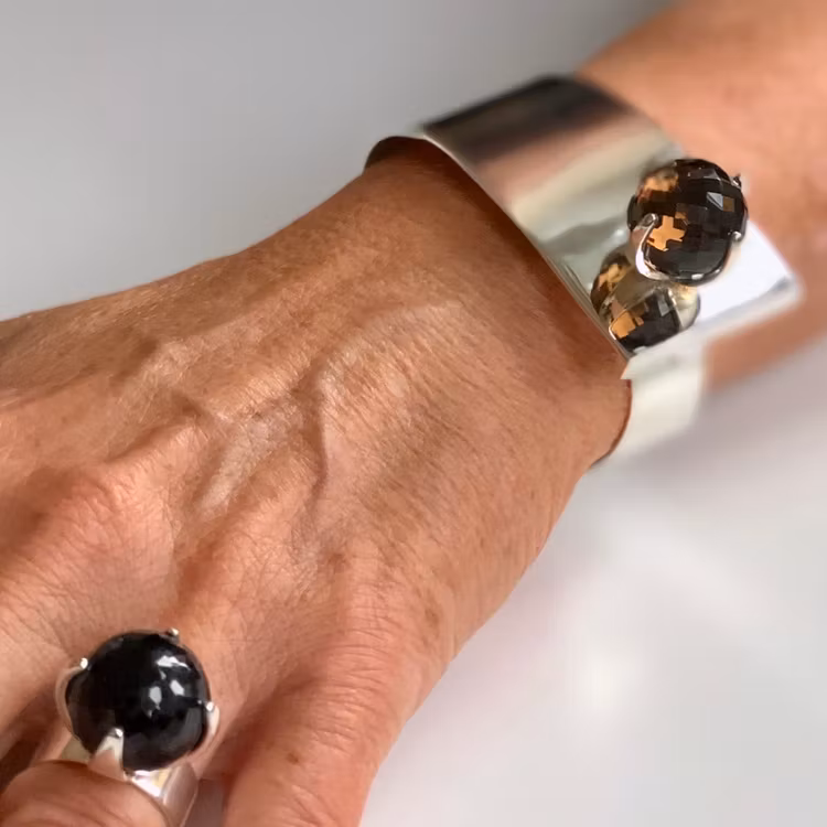 Hand med stor silverring och silverarmband med rökkvarts. Hand with big silverring and silver bracelet with smokey quartz.