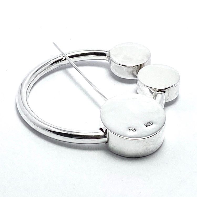 rund silverbrosch med form av omega. round silver brooch with the design from omega.