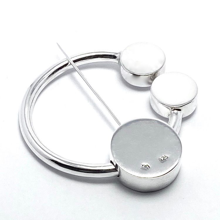 rund silverbrosch med form av omega. round silver brooch with the design from omega.