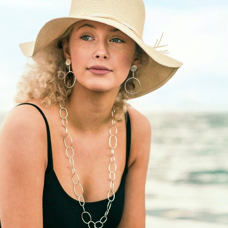 kvinna med långt silverhalsband med runda länkar i olika storlekar. woman with long silver chain with round links in various sizes.