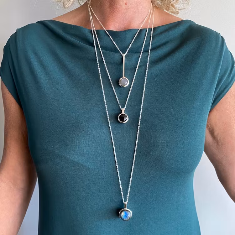 Modell med tre olika längder av silverkedjor och olika silverhängen. Model with three various lengths of silver chains with pendants