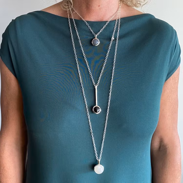 Modell med tre olika längder av silverkedjor och olika silverhängen. Model with three various lengths of silver chains with pendants