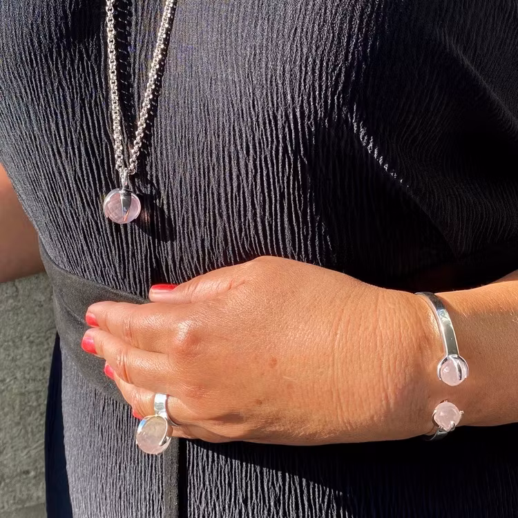 Kvinna med matchande armband, hänge, och ring med rosenkvarts. Woman with matching ring, pendant and bracelet with rose quartz