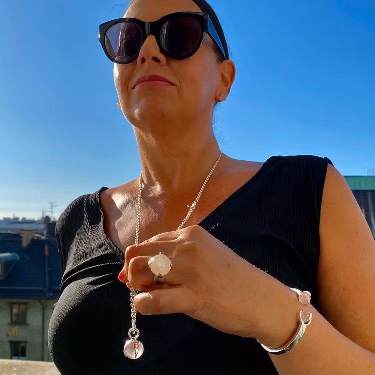 Kvinna med matchande armband, hänge, ring och örhängen med rosenkvarts. Woman with matching earrings, ring, pendant and bracelet with rose quartz