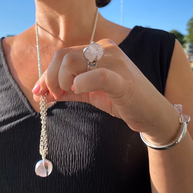 Kvinna med matchande armband, hänge och ring med rosenkvarts. Woman with matching ring, pendant and bracelet with rose quartz