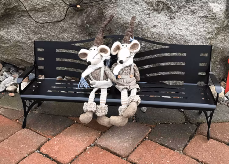 Två gosedjur sittandes på en liten parkbänk i plåt.