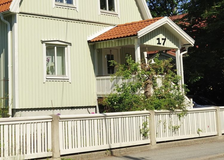 Hussiffror i metall mot träfasad över entré.