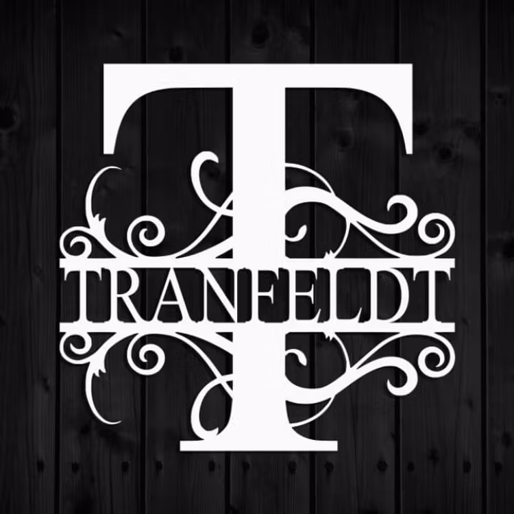 Vitt personligt monogram med namnet Tranfeldt mot svart väggpanel.