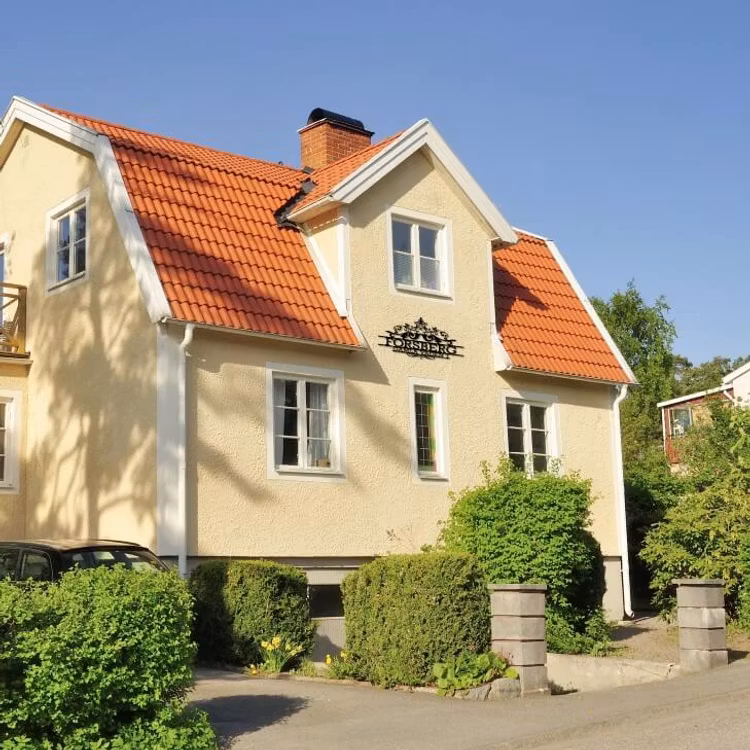 Exklusiv husdekoration med efternamn, gatunamn samt gatunummer på ett stort gult hus.