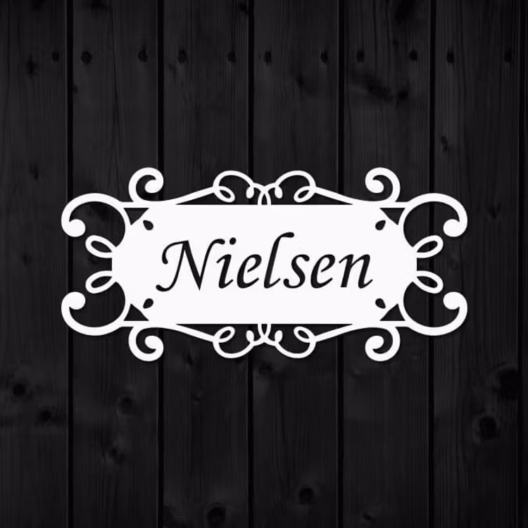 Namnskylt i metall med namnet Nielsen utskuret.
