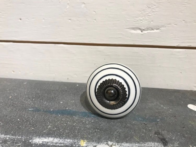Vit keramikknopp med svarta ränder.