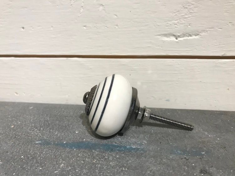 Vit keramikknopp med svarta ränder.
