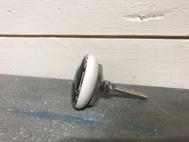 Svart keramikknopp med text och krona