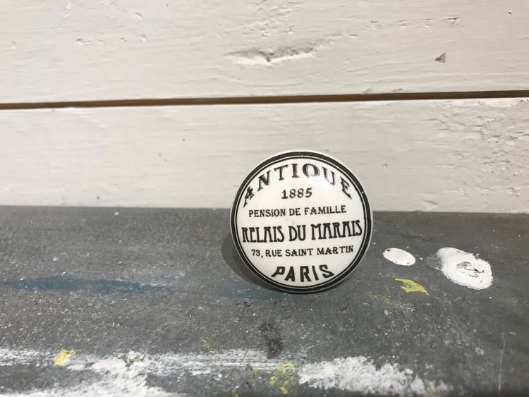 Vit keramikknopp med svart text, Antique, Paris.