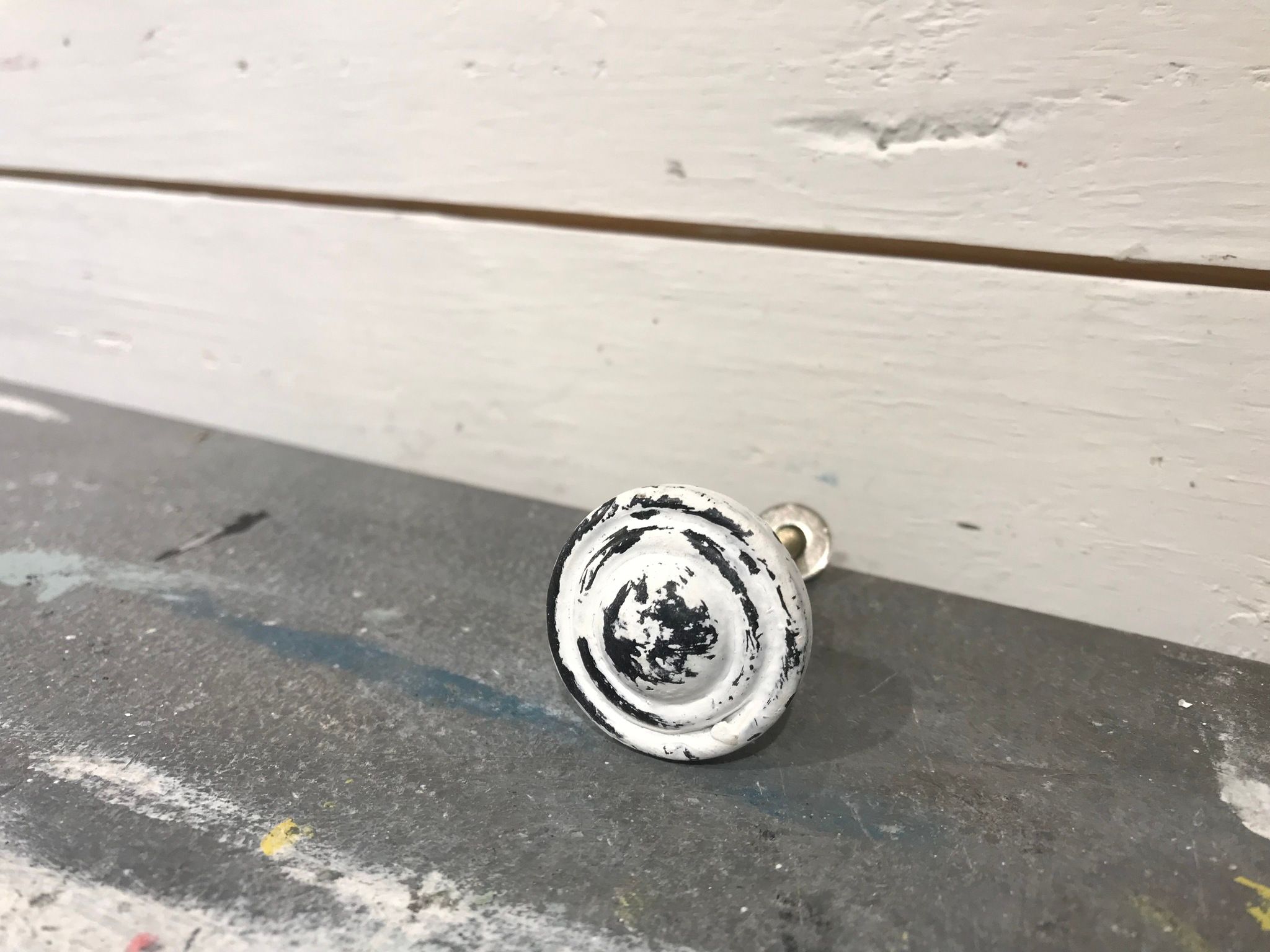 Knopp i metall, vit med slitningar i svart