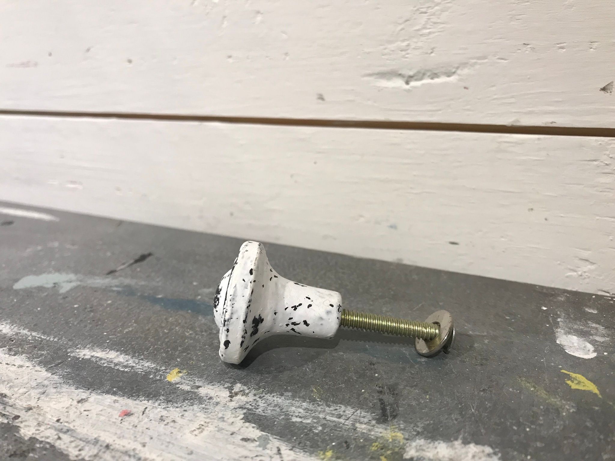 Knopp i metall, vit med slitningar i svart