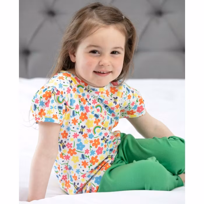 Somrig T-shirt för barn i ekologisk bomull – lekfull design med regnbågar & blommor