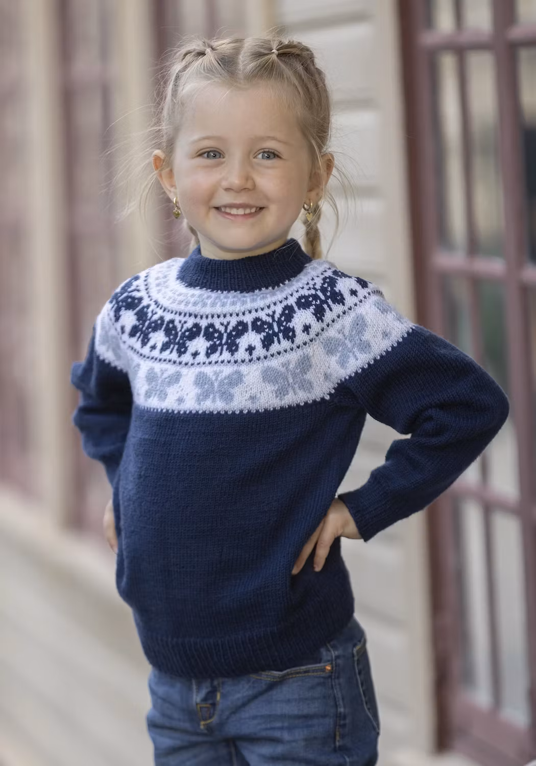 Stickad barntröja "Butterfly" i marin med vitt och ljusblått fjärilsmönster runt oket.