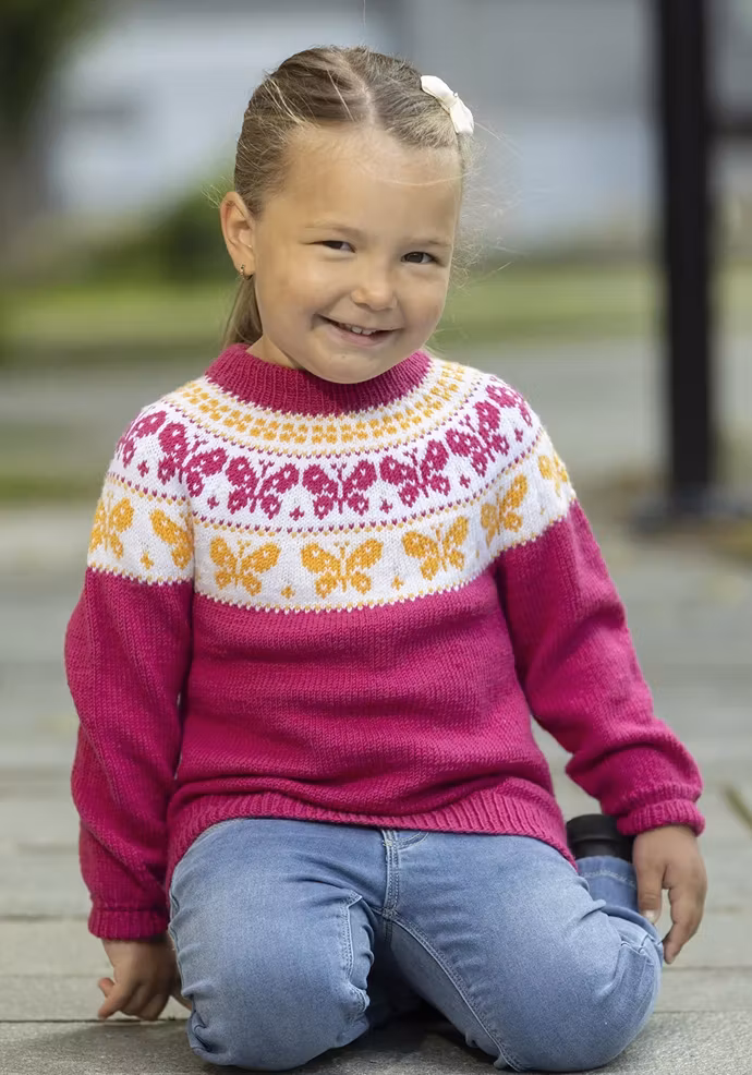 Stickad barntröja "Butterfly" i cerise med vitt och gult fjärilsmönster runt oket.