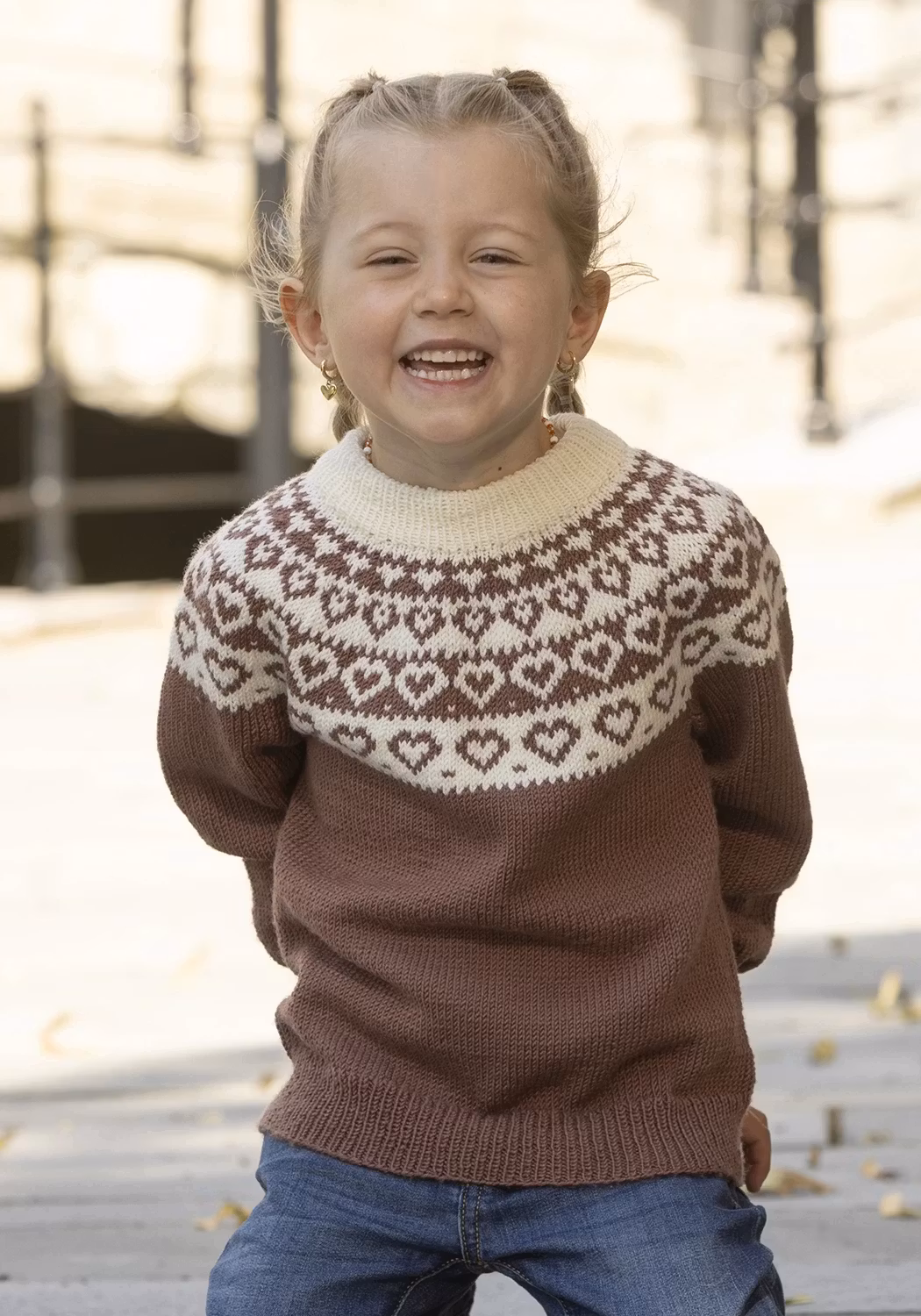 Stickad barntröja "Hjerte" i rödbrun med naturvit hjärtbård runt oket.