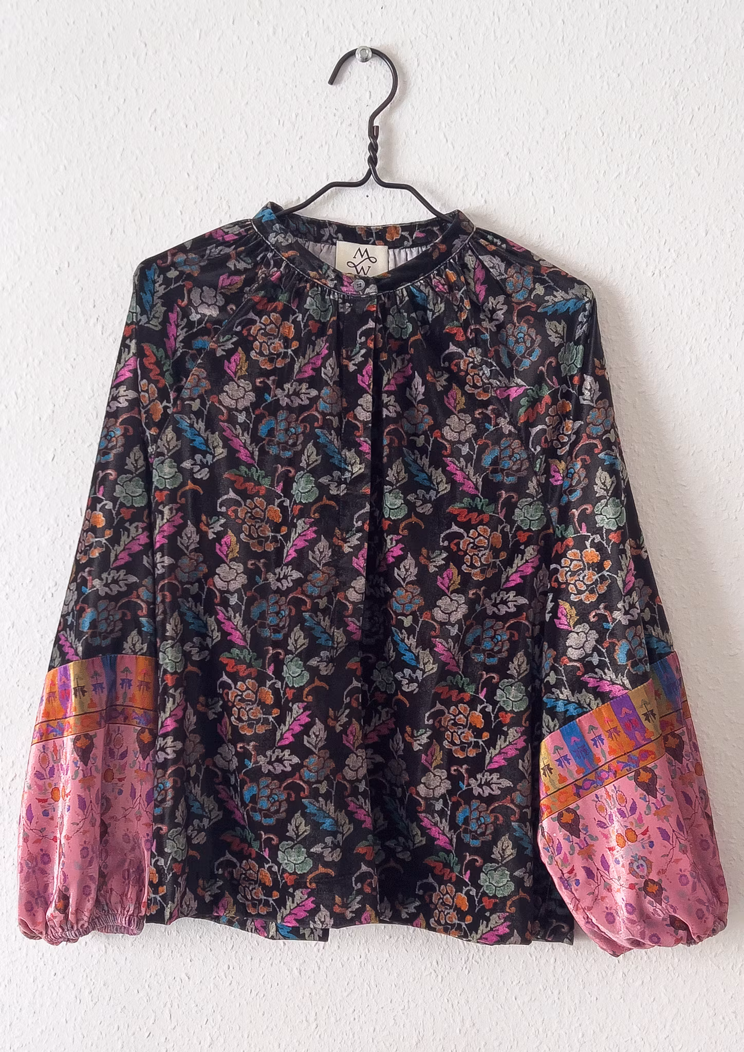 Svart blus med rosa ärmar i mjuk tunn velour, med vackert print. Puffärm och knappar framtill. M Wiesneck