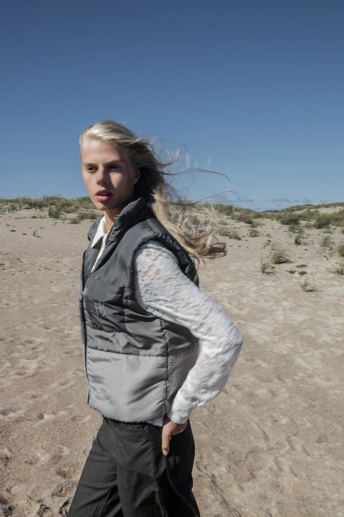 Sportig väst i lätt material med foder, tre gröna toner och tryck i reflex baktill. Från Humble by Sofie