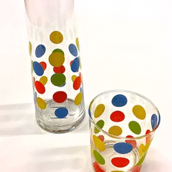 Dots en en glaskaraff och glas med blå, gröna, gula, röda och oranga prickar.