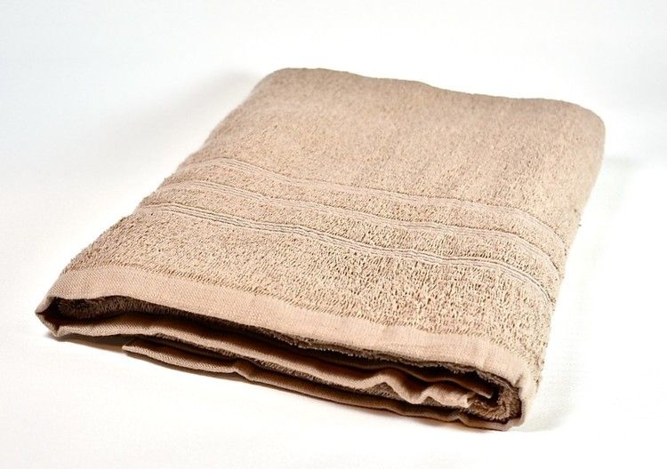 Soft ett beige frottébadlakan i 100% bomull från Noble house, mått: 70 x 130 cm.