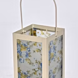 Lykta Blå rosor. Färg: En cremefärgad lykta med vitt glas med blå rosor och gröna blad.