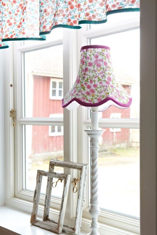 Doris en lampskärm från Boel & Jan med vågad kant. Färg: Vit med aprikos och gula blommor med gröna blad och gröna kantband.