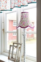 Doris en lampskärm från Boel & Jan med vågad kant. Färg: Vit med aprikos och gula blommor med gröna blad och gröna kantband.