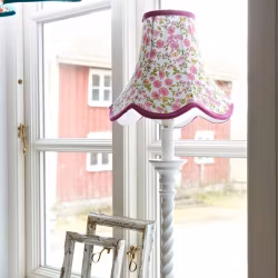 Doris en lampskärm från Boel & Jan med vågad kant. Färg: Vit med prickar i grönt, aprikos och rött med gröna kantband.