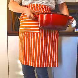 Poppy ett orange och vitrandigt förkläde i 100% bomull från Noble house, mått 60 x 75 cm.