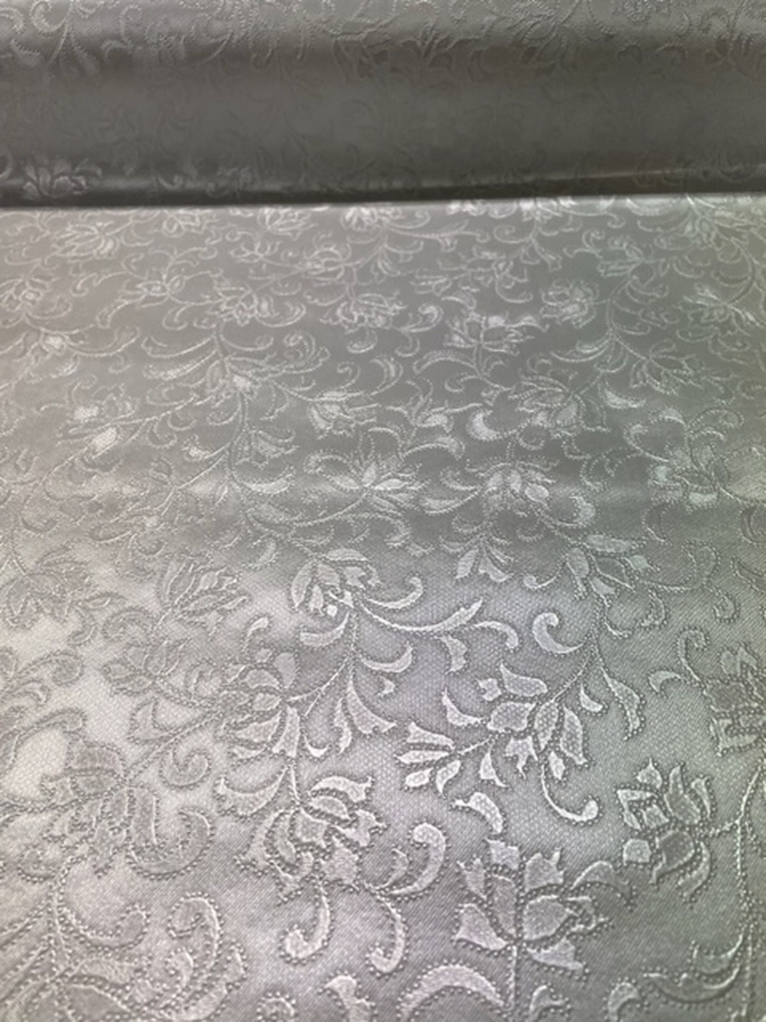 Brodyr en grå/silverfärgad vaxduk med ett ¨broderat¨ mönster på metervara i bredd 140 cm