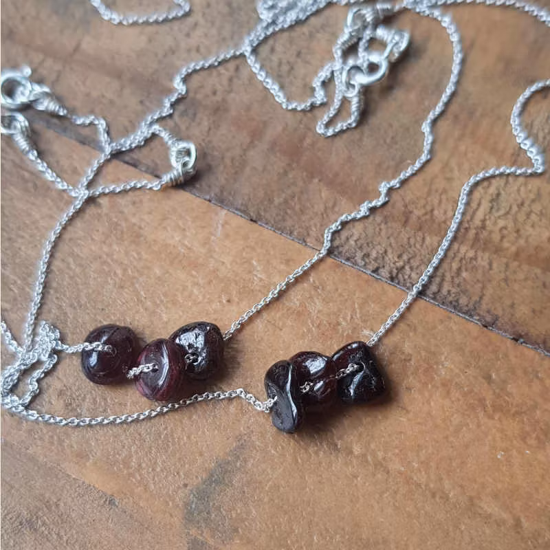 Två exempel på silverhalsband med granat, månadssten januari.
