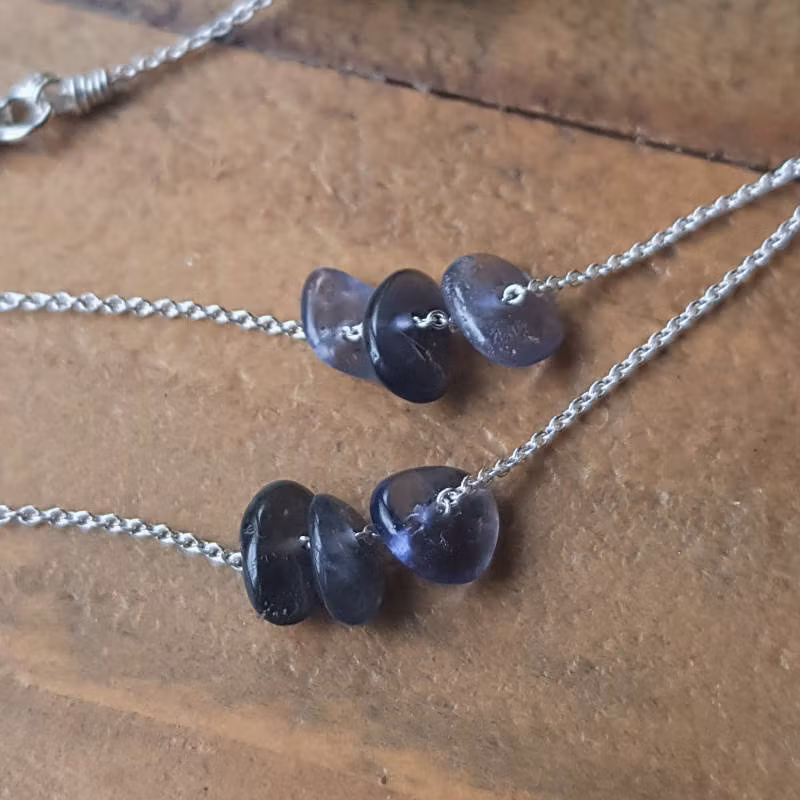 Två exempel på silverhalsband med iloit, månadssten för september. Stenarna skiftar naturligt i nyans, form & uttryck.